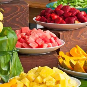 Assorted fruits including pineapple, watermelon, strawberries, and melons on a buffet table.